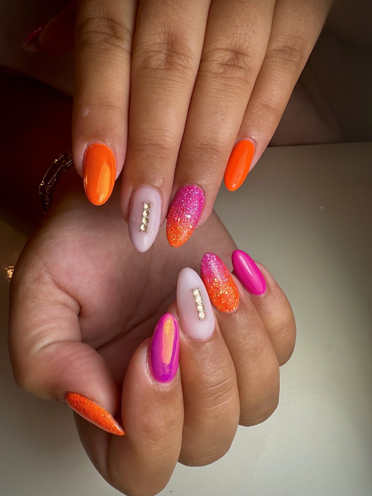 Amandelnagels in oranje en roze glitter met gouden studs